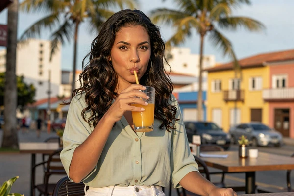 Brazilian woman enjoying a fresh juice at a tropical outdoor café in Brazil