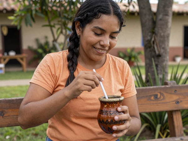 Paraguayan woman preparing traditional tereré drink in a guampa cup in her garden