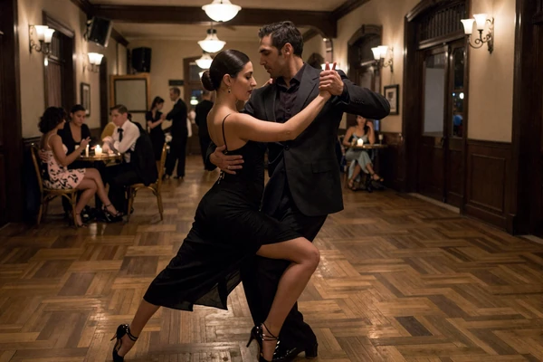 Couple dancing tango in an intimate Buenos Aires milonga with candlelight and vintage decor