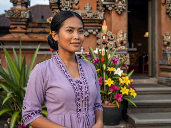 Javanese-Surinamese woman near a Hindu temple in Paramaribo with tropical flowers